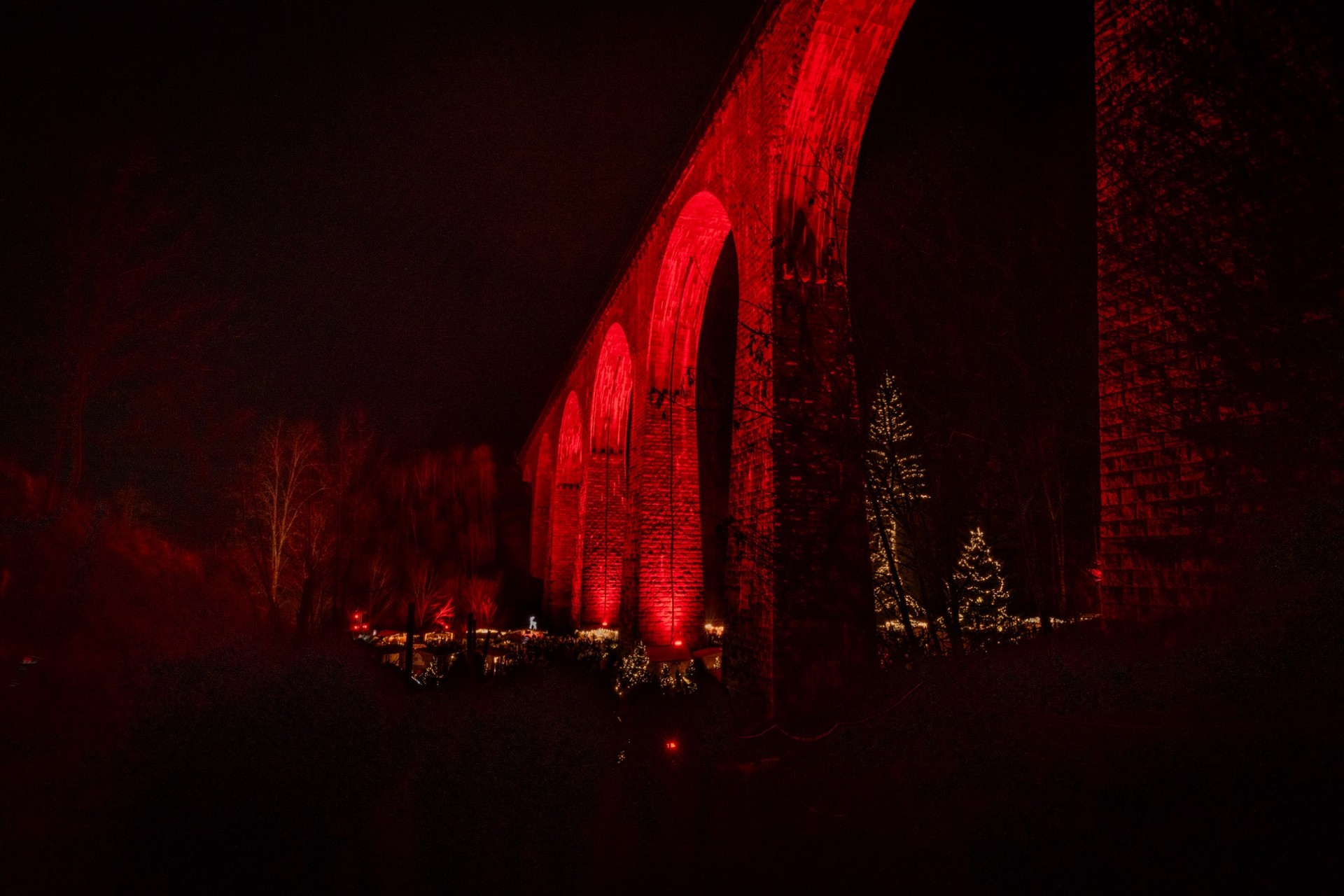 Rot illuminiertes Ravennaviadukt über dem Weihnachtsmarkt in der Ravennaschlucht